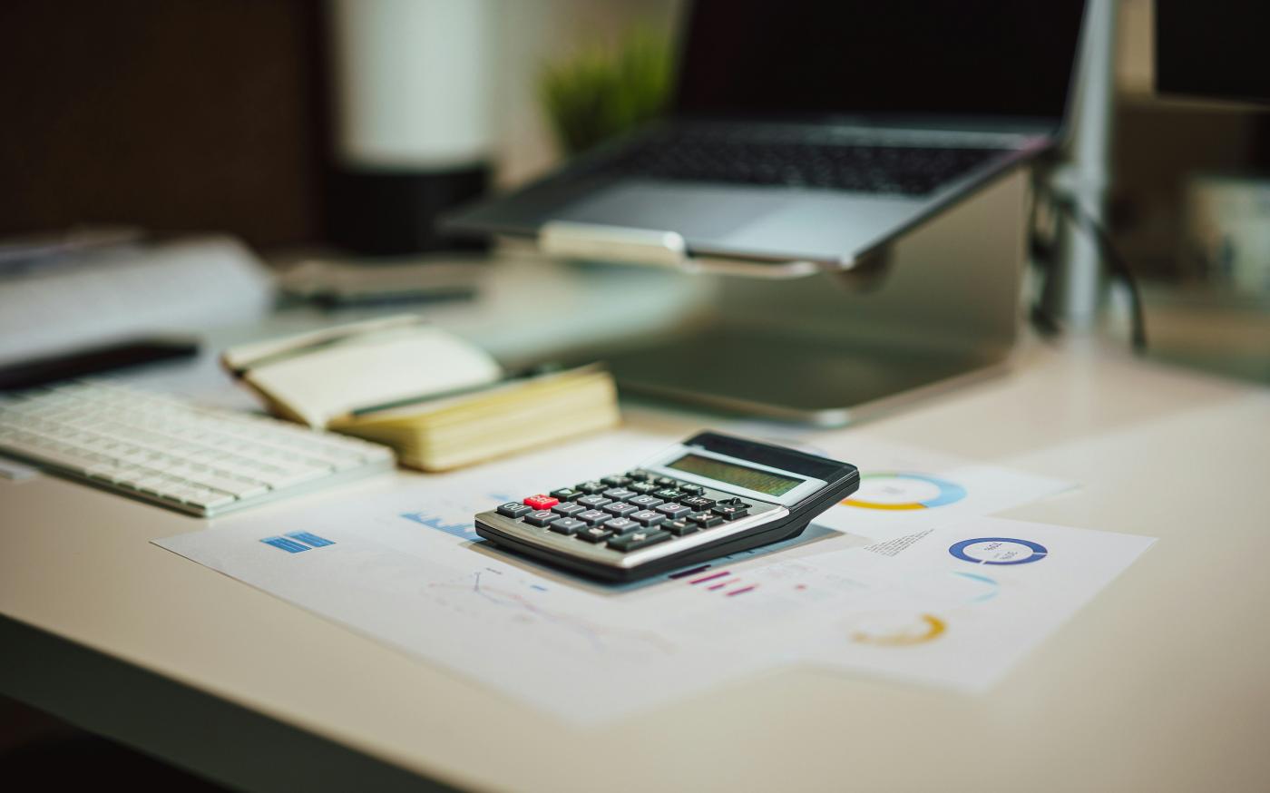 a calculator sitting on top of a table next to a laptop by Jakub Żerdzicki courtesy of Unsplash.