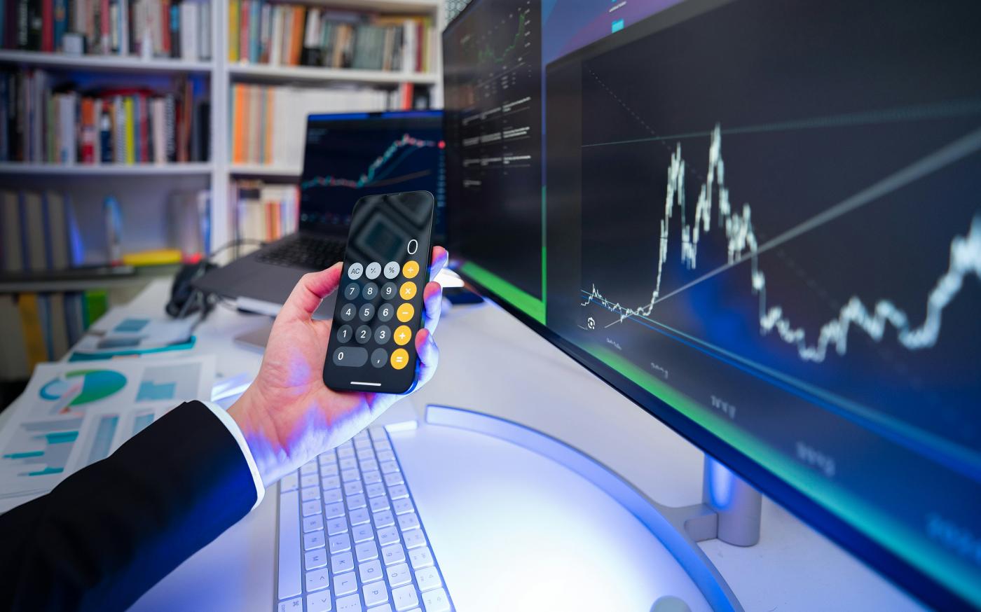 A man holding a remote control in front of a computer by Jakub Żerdzicki courtesy of Unsplash.