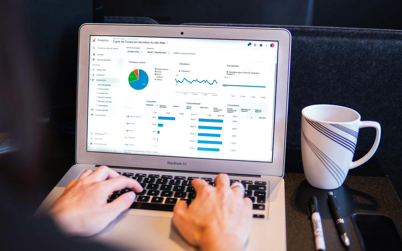 person using macbook pro on black table by Myriam Jessier courtesy of Unsplash.