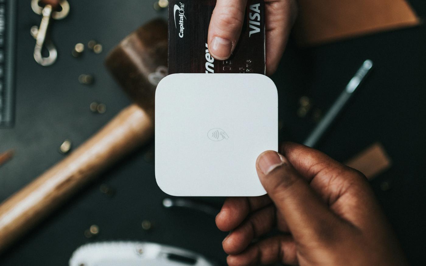 person holding Visa card and white device by Nathan Dumlao courtesy of Unsplash.