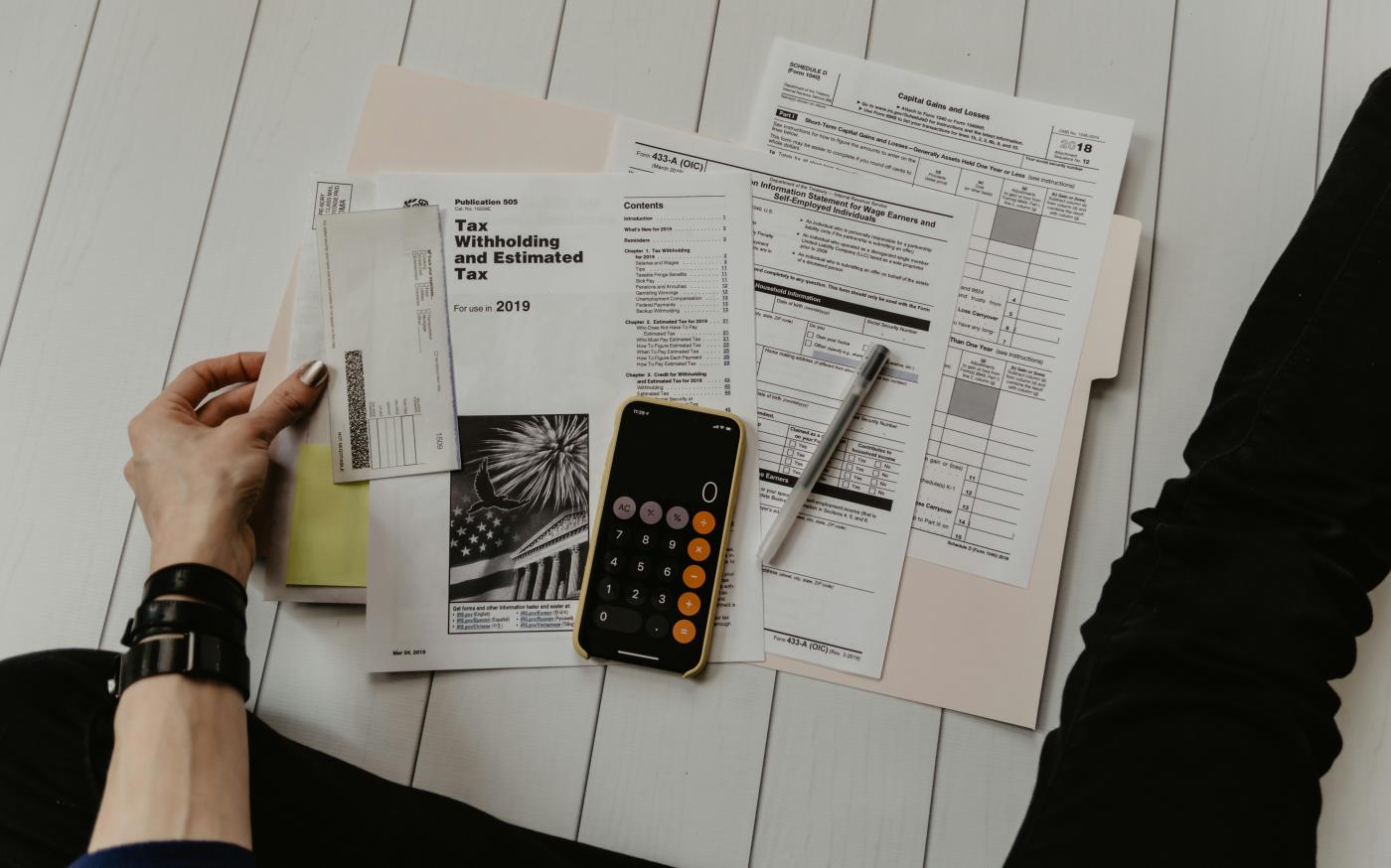 person holding paper near pen and calculator by Kelly Sikkema courtesy of Unsplash.