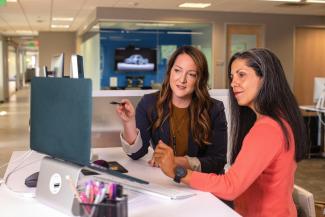 two women sitting at a table looking at a computer screen by LinkedIn Sales Solutions courtesy of Unsplash.