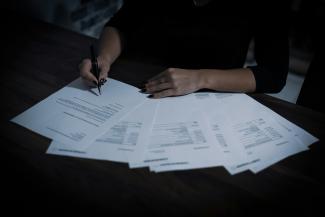 a woman sitting at a table with lots of papers by Dimitri Karastelev courtesy of Unsplash.