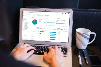 person using macbook pro on black table by Myriam Jessier courtesy of Unsplash.