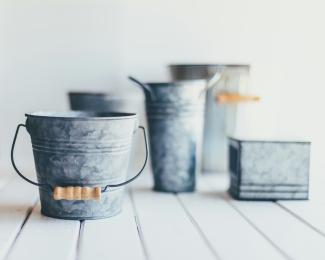 gray steel bucket on brown wooden bucket by Sixteen Miles Out courtesy of Unsplash.