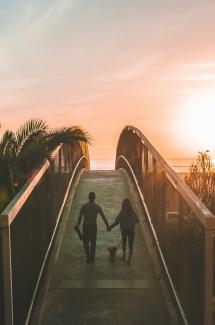 man and woman holding hand while walking on bridge by Shea Rouda courtesy of Unsplash.