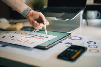 person using stylus on tablet with charts by Jakub Żerdzicki courtesy of Unsplash.